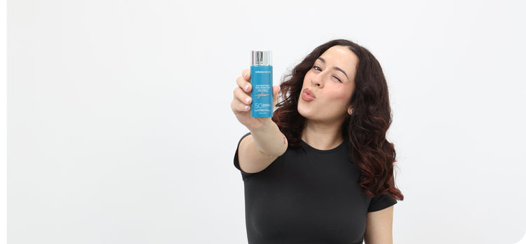 Women in a black shirt holding a Colorescience Sunforgettable Flex Glow SPF product.