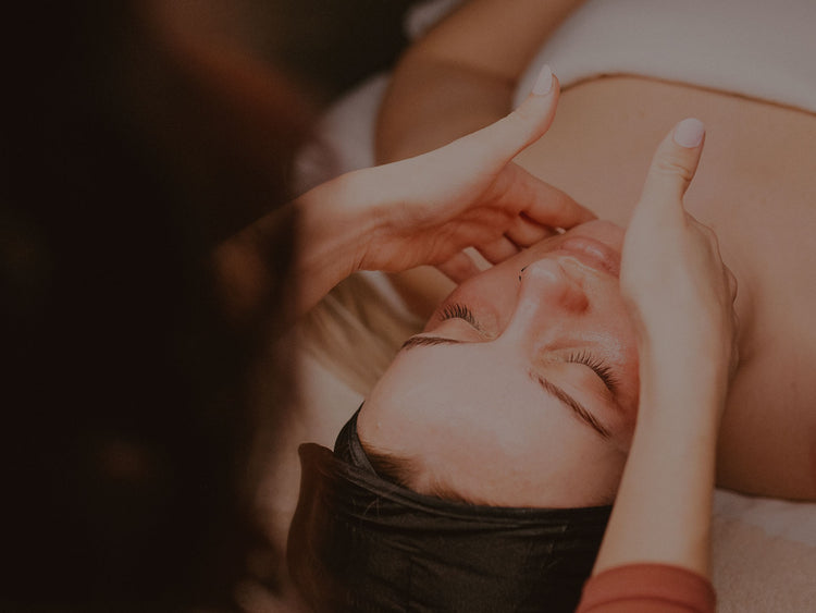 Women laying down with her eyes closed receiving a facial massage