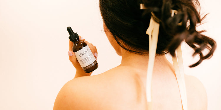 Women with her back facing the camera holding a glymed skincare product.